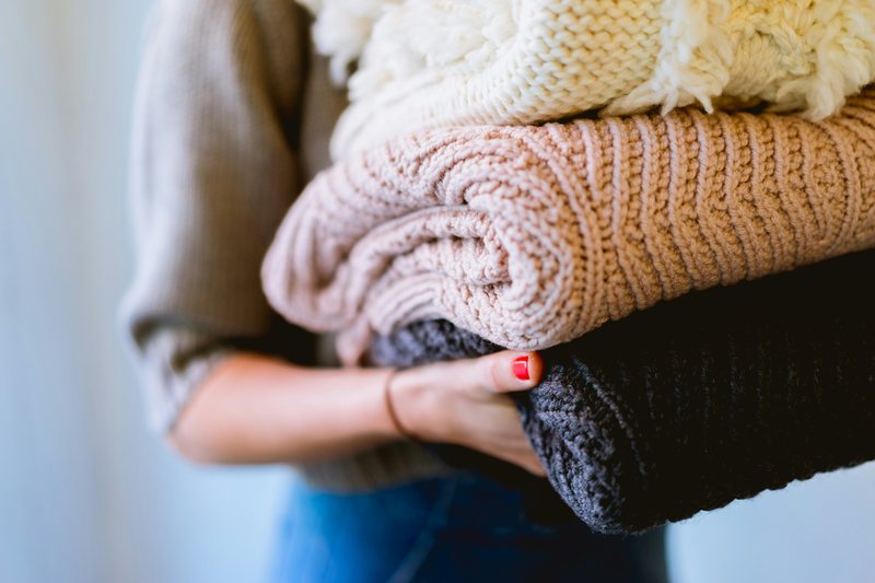 Carrying a stack of freshly folded sweaters and blankets